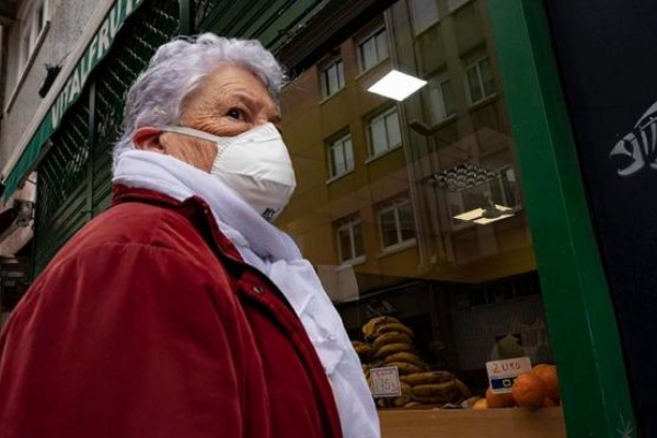 Una mujer espera en la entrada de un local comercial durante el estado de alarma provocado por la crisis del coronavirus