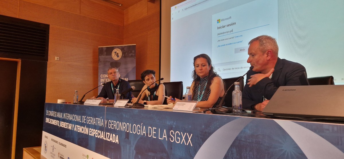 Mesa de ponentes del Simposium 1 del Congreso SGXX con José Manuel Pérez, Ester Micó, José Pascual Bueno y la moderadora María Elena Mosquera, frente a una pantalla con inicio de sesión proyectado.
